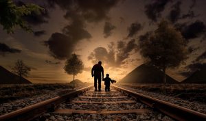 A father and son walking on the rails.